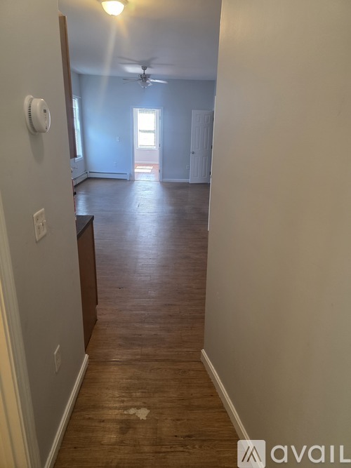 A long hallway with a fan and light on the wall.