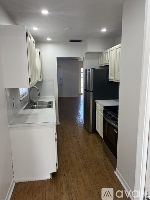 A kitchen with white cabinets and a black fridge.