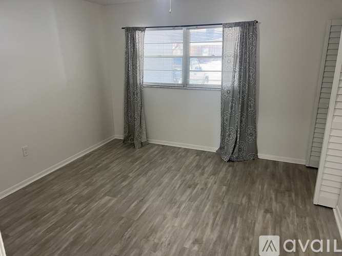 A room with a window and grey curtains.