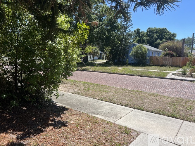 A residential area with a house, trees, and a sidewalk.