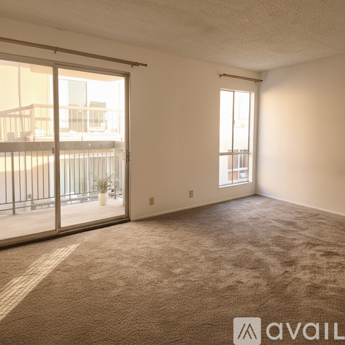 A room with a carpeted floor and a sliding glass door leading to a balcony.