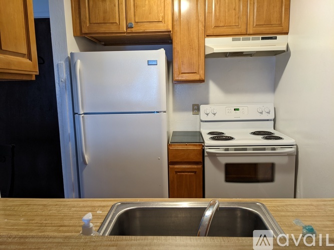 A kitchen with a white refrigerator, white stove, and wooden cabinets.