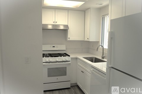 A kitchen with white cabinets and appliances.