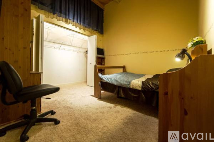 A bedroom with a bed, desk, and chair.