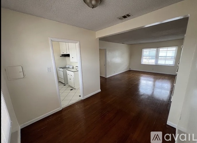 A room with wooden floors and a small kitchenette.