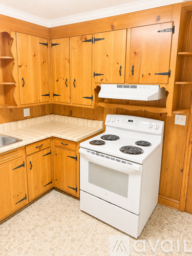 A kitchen with wooden cabinets and a white stove.