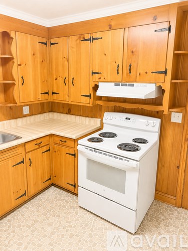 A kitchen with wooden cabinets and a white stove.