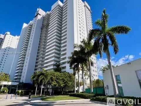 A tall white building with a palm tree in front of it.