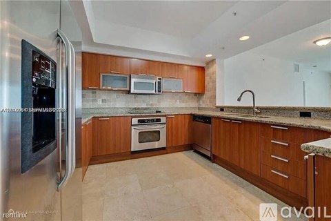 A kitchen with a stainless steel refrigerator and wooden cabinets.
