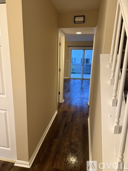 A hallway with a white door and a white railing.