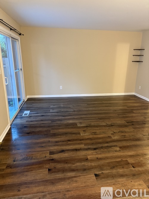 A room with wooden flooring and a sliding glass door.