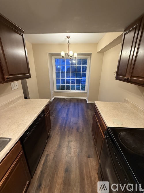 A kitchen with dark wood cabinets and a window with blue curtains.