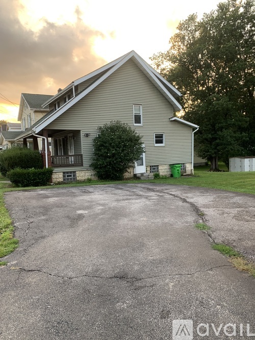 A house with a grey roof and a driveway in front of it.