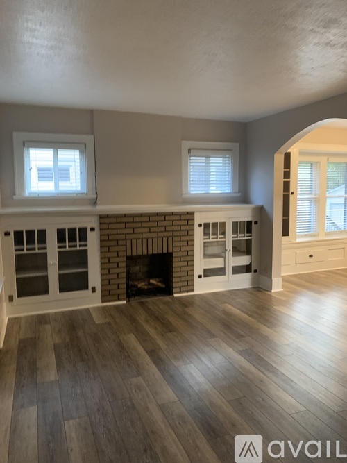 A living room with a fireplace and two windows.