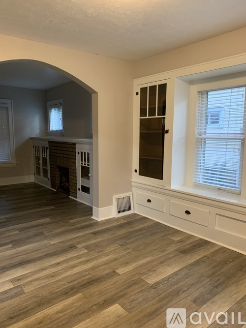 A room with wooden flooring and a window with blinds.