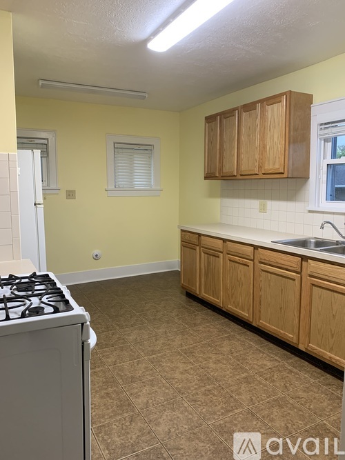 A kitchen with a stove, cabinets, and a window.