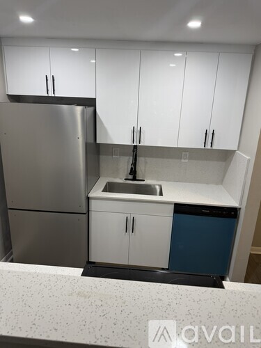 A kitchen with white cabinets and a stainless steel refrigerator.