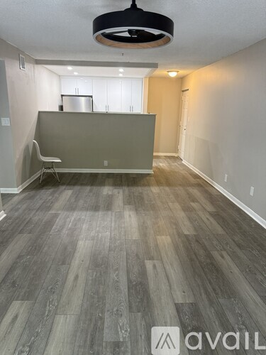 A room with a grey floor and a black ceiling fan.