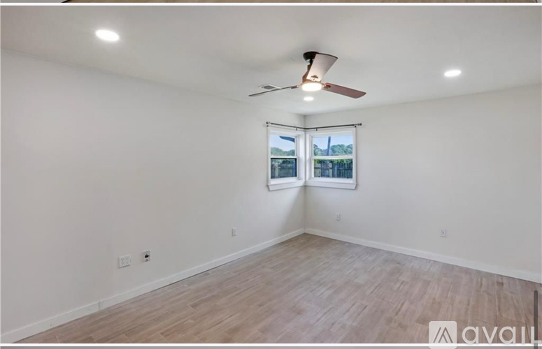 A room with a ceiling fan and a window with blinds.