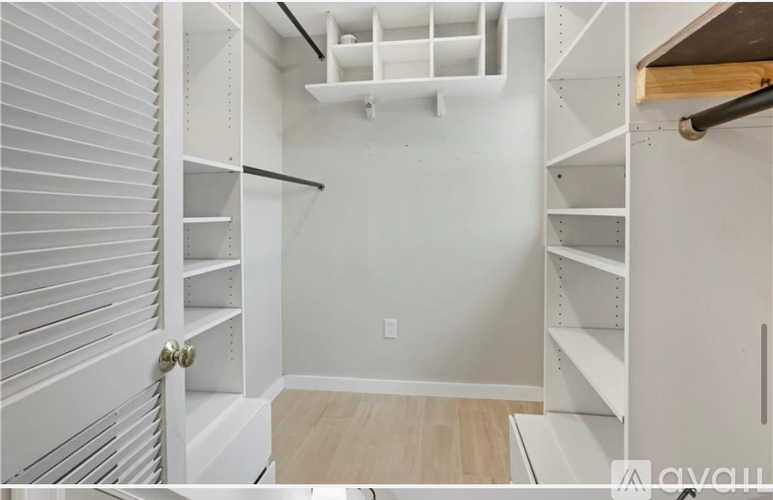 A white pantry with a door on the left and a shelf on the right.