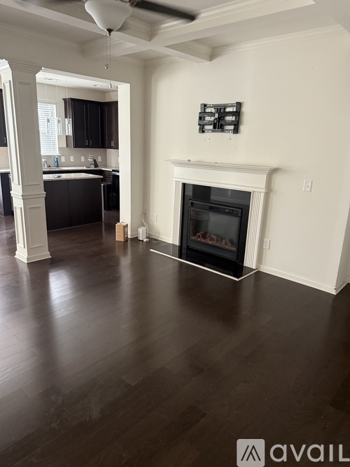 A living room with a fireplace and dark wood floors.