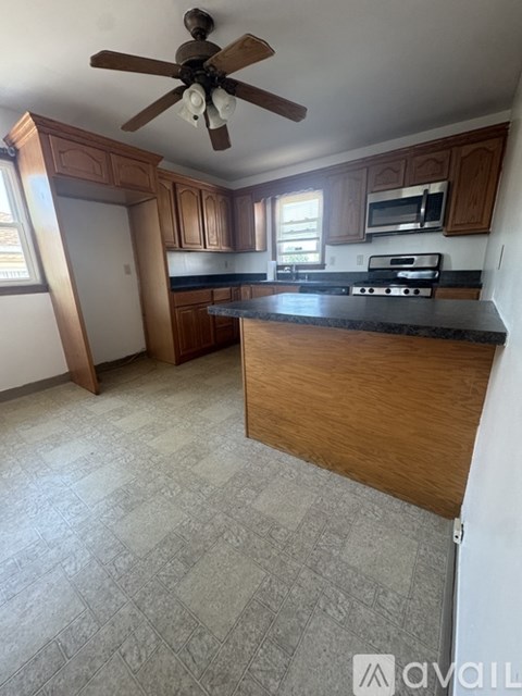 A kitchen with a black counter top and wooden cabinets.