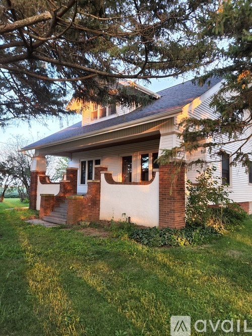 A house with a white exterior and a brown roof is surrounded by trees.