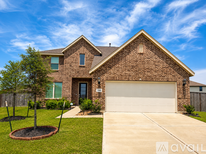 A brick house with a white garage door and a tree in a circular hole in the lawn.