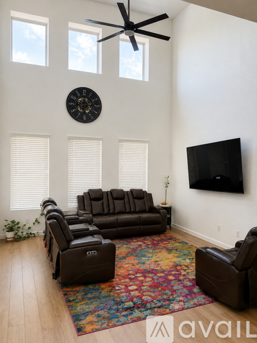 A living room with a brown leather couch and a fan on the ceiling.
