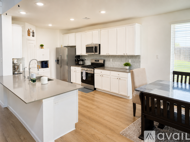 A kitchen with white cabinets and a wooden floor.