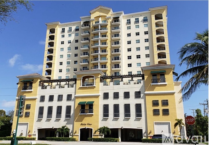 A large yellow building with a balcony on the top floor.