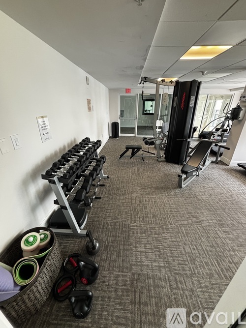 A gym with a variety of equipment including dumbbells, a treadmill, and a squat rack.