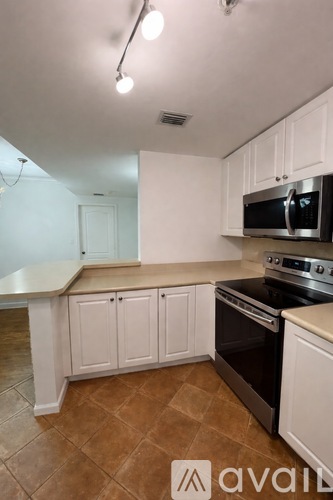 A kitchen with white cabinets and a black microwave.