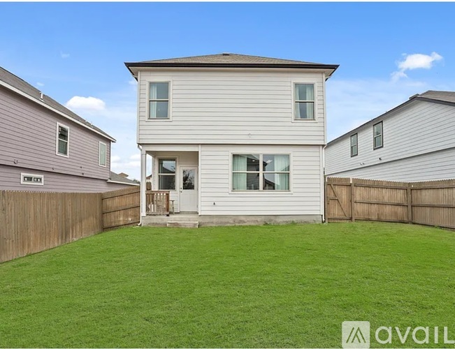 A house with a fence and a green lawn in front.