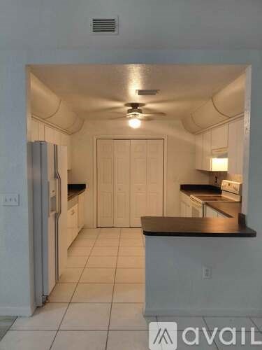 A kitchen with white cabinets and a black countertop.