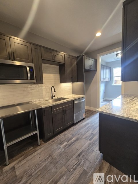 A kitchen with dark wood cabinets and a marble countertop.