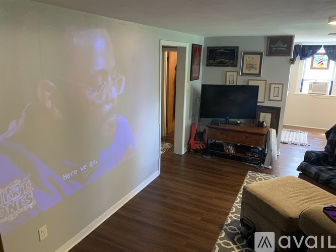 A living room with a television and a wall with a picture of a man.