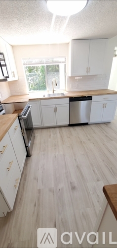 A kitchen with white cabinets and a wooden floor.