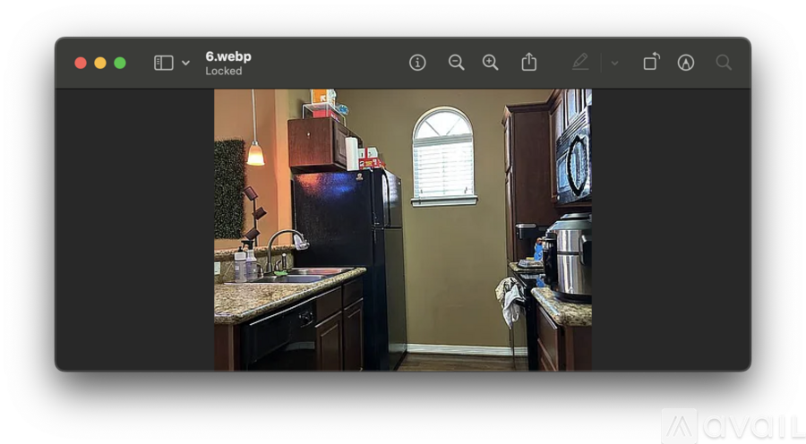 A kitchen with a refrigerator, a window, and a clock on the wall.