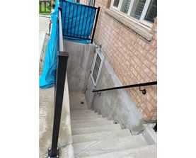 A set of stairs with a black railing and a blue tarp on the wall.