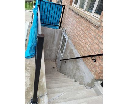 A set of stairs with a black railing and a blue tarp on the wall.
