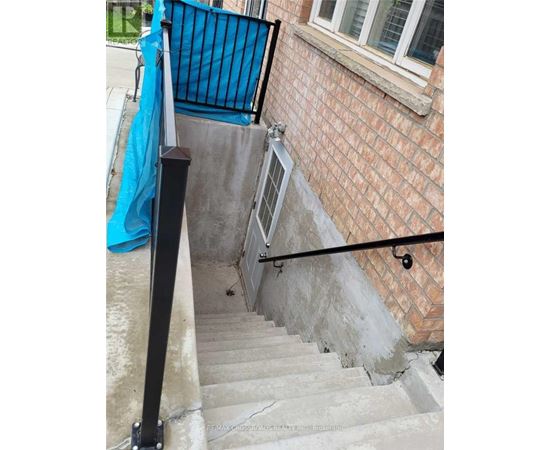 A set of stairs with a black railing and a blue tarp on the wall.