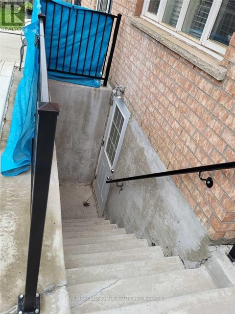 A set of stairs with a black railing and a blue tarp on the wall.