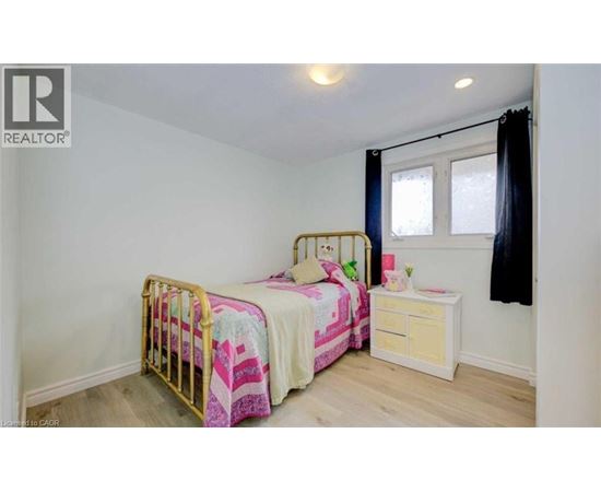 A bedroom with two beds and a nightstand.