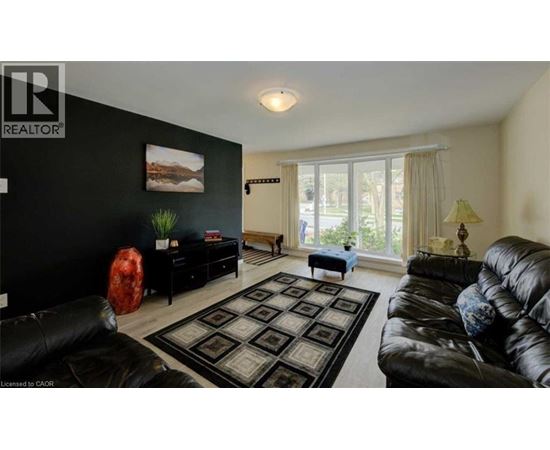 A living room with a black couch and a rug.