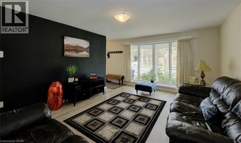A living room with a black couch and a rug.