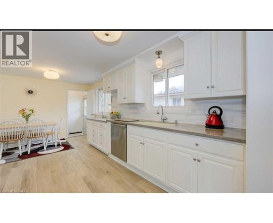 A kitchen with white cabinets and a wooden floor.