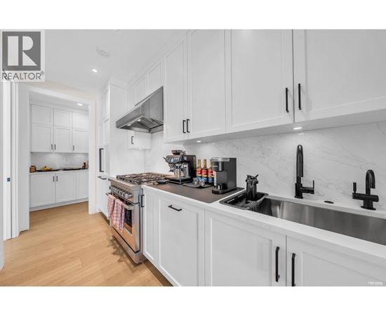 A modern kitchen with white cabinets and stainless steel appliances.