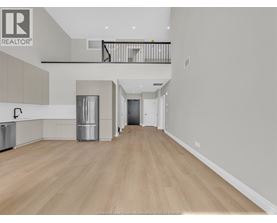 A spacious, empty room with wooden flooring and a balcony.