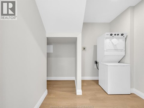 A white kitchen appliance sits in a corner of a white room.